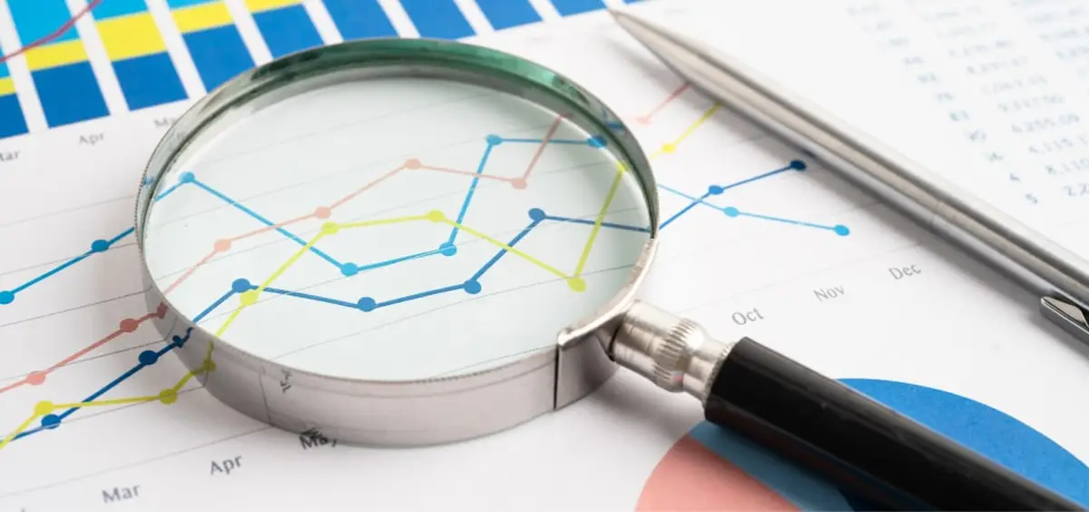 Magnifying glass over colorful line graphs with pen