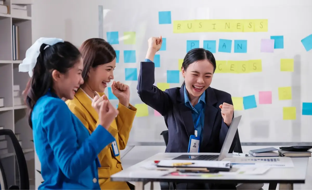 Three women celebrating business success in office